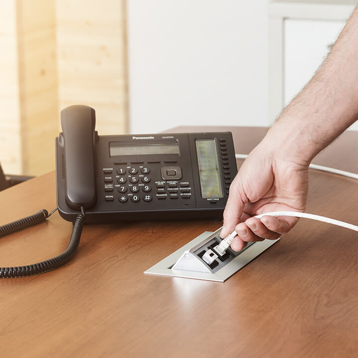 Un homme branche un câble cuivre/fibre optique pour la téléphonie IP